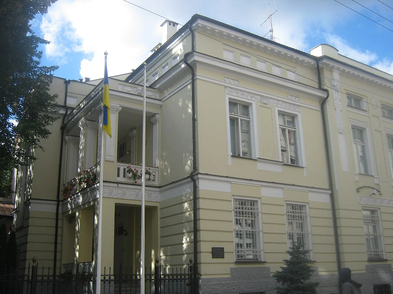 Класична світла будівля з українським прапором на балконі та колонами